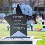 childs blue teddy bear peering over a star gravestone