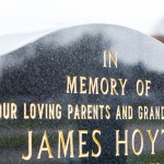 V-cut gilded letters stand out on a black granite memoria